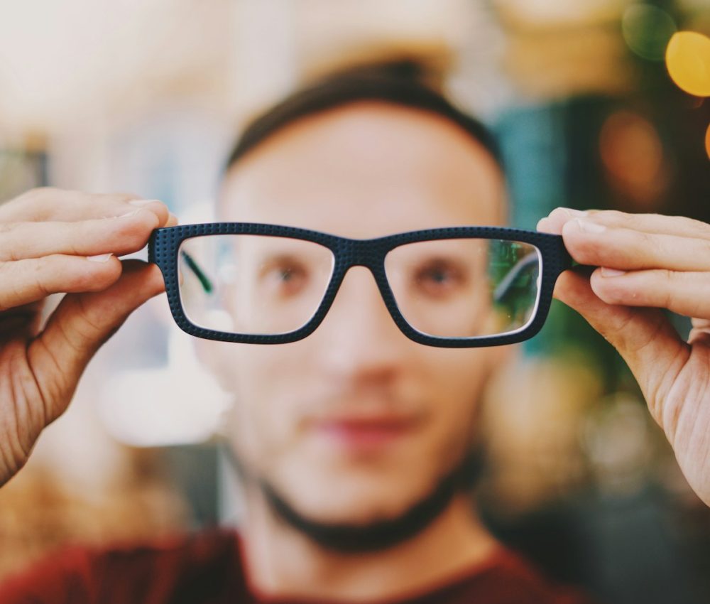 person holding eyeglasses with black frames